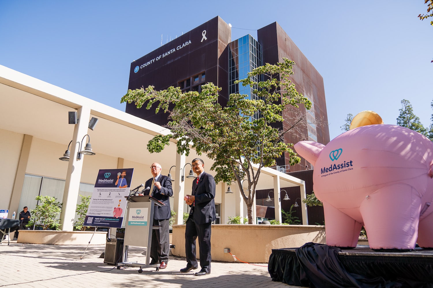 Photo of Supervisors Simitian and Lee with inflatable Piggy Bank to their right in front of the County Office Building of Santa Clara.