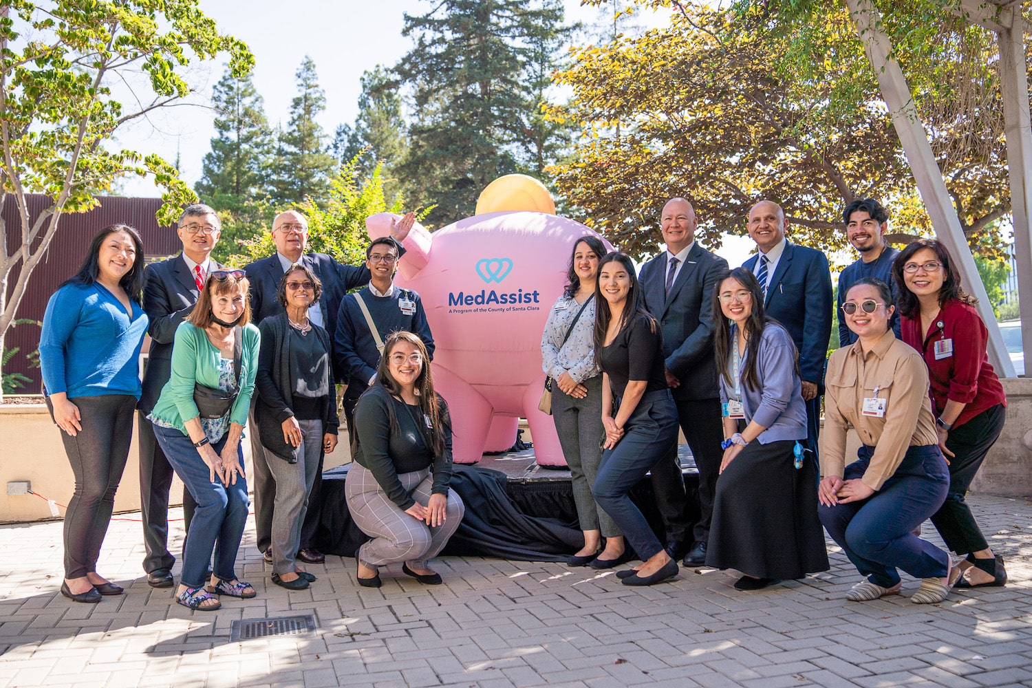 Photo of MedAssist Team posing in front of MedAssist piggy bank.